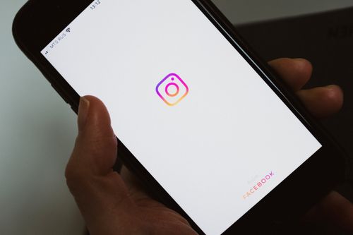 Free Crop faceless person taking mobile phone and demonstrating blank screen with social media app logo while having break and surfing internet Stock Photo