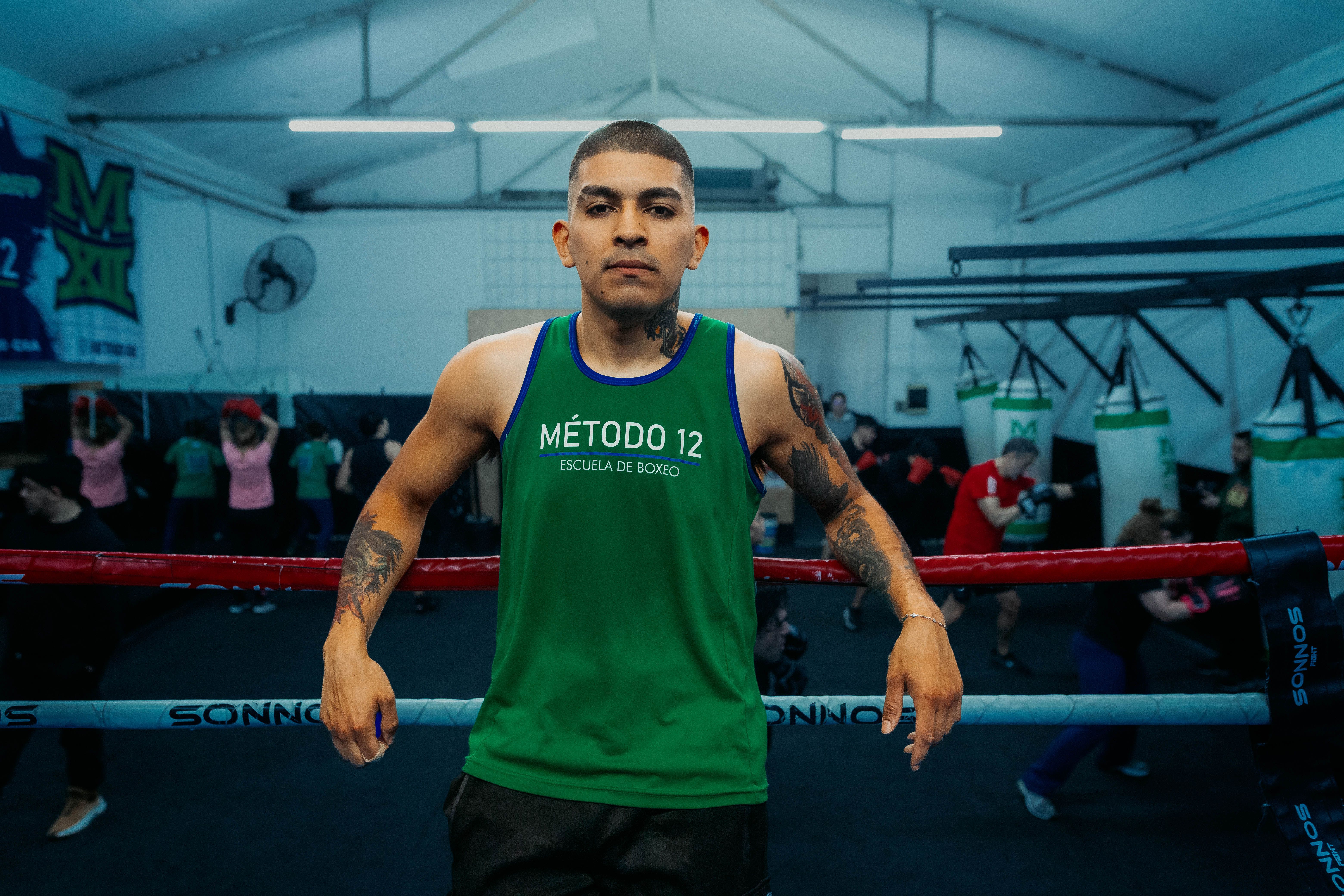 A confident boxing instructor poses in a vibrant Buenos Aires gym environment.