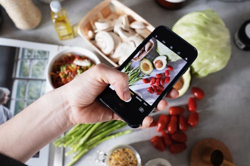 Person Holding Black Smartphone Taking Photos Of Food 