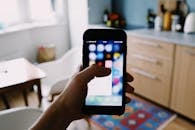 Crop faceless person showing application icon on smartphone screen