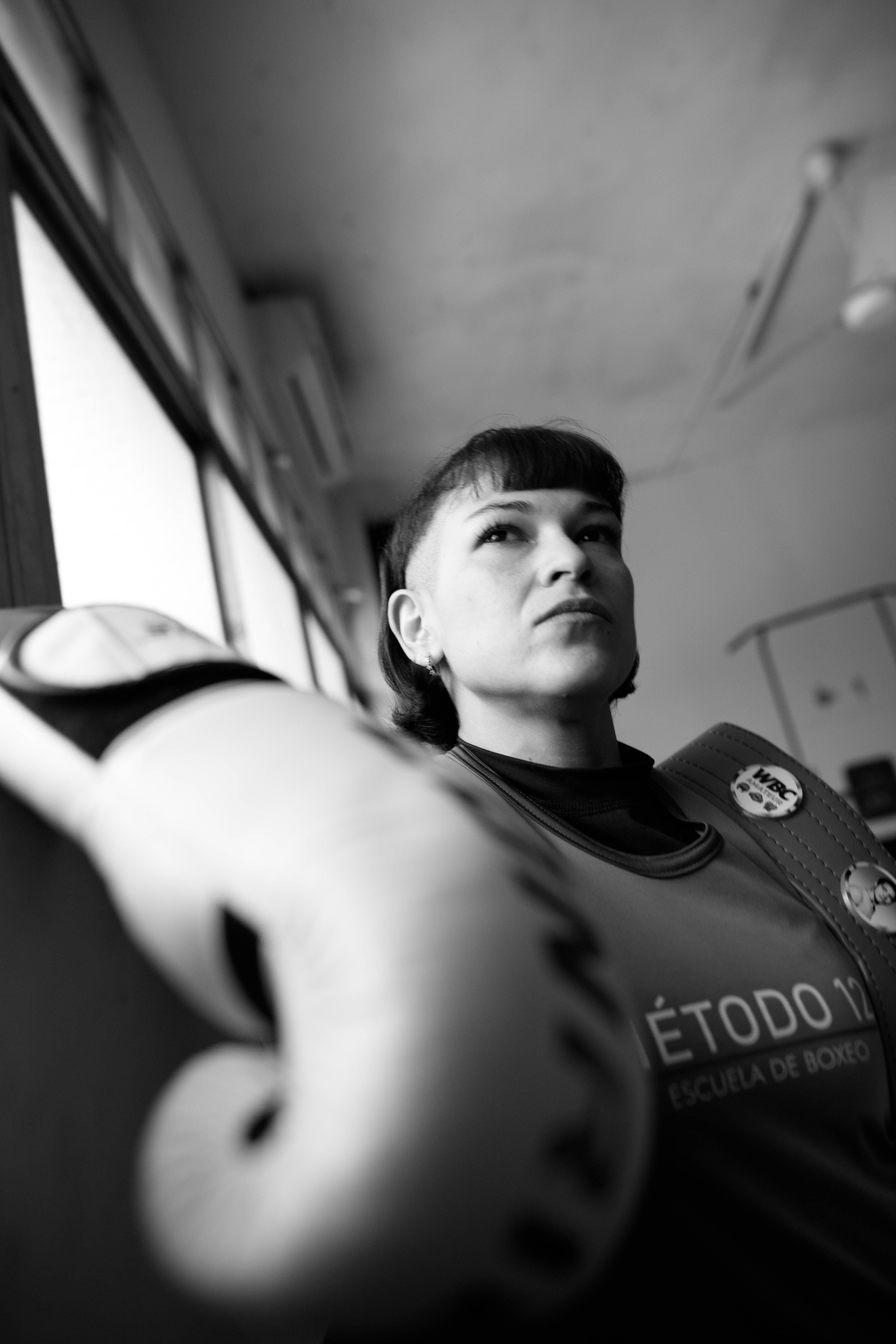 Black and white portrait of a female boxer in a Buenos Aires gym, exuding determination.