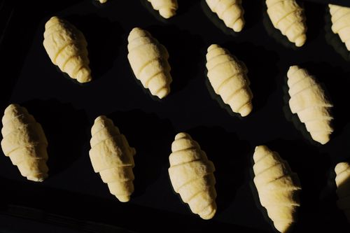 Free Top view composition of uncooked raw croissant dough arranged on surface of black glass in dark light Stock Photo