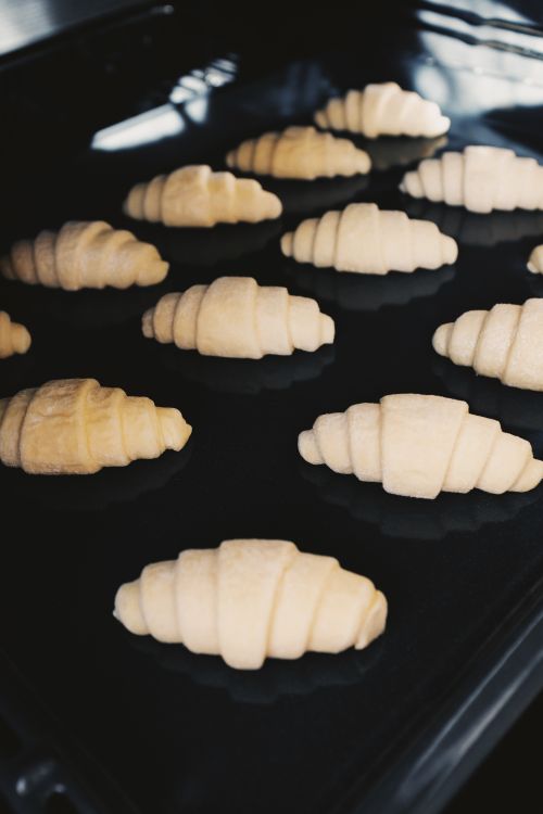 Free From above of unbaked croissants placed on black iron mold during cooking pastry preparation stage before going to oven Stock Photo