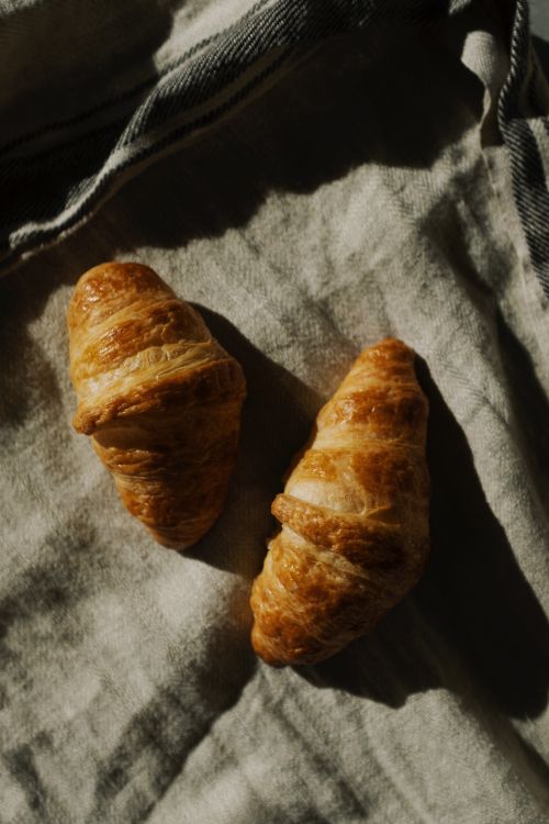 Free Top view of two golden croissants on a textured cloth, showcasing their flaky layers. Stock Photo