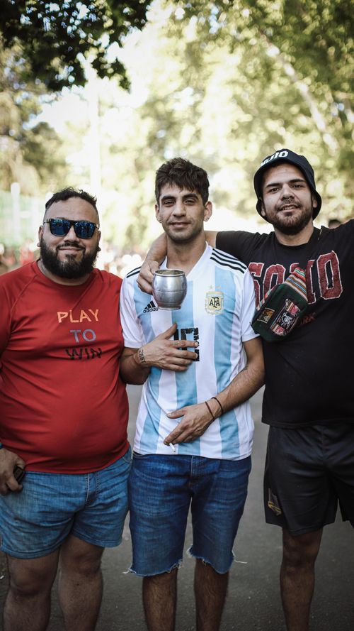 Free Three Argentinian fans celebrate outdoors with a trophy cup in Buenos Aires. Stock Photo
