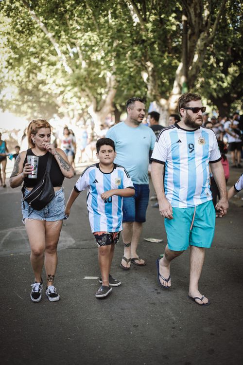 Free Happy soccer fans wearing Argentina jerseys walk through Buenos Aires, enjoying a sunny day. Stock Photo