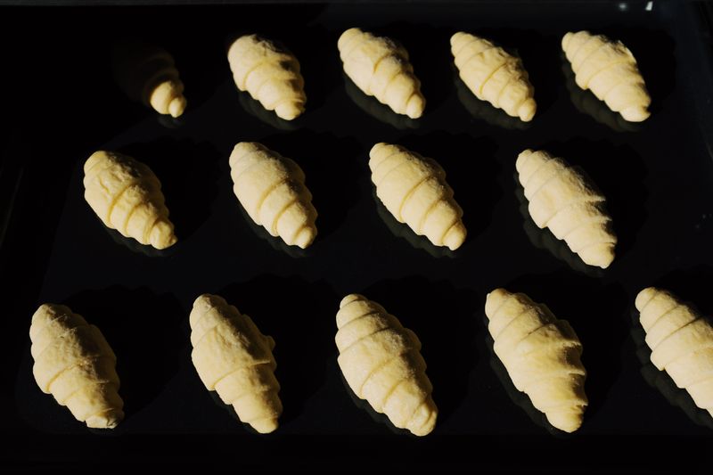 Fresh unbaked croissants aligned on a tray, capturing the essence of baking in progress.