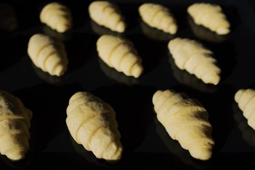 Free Close-up of unbaked croissants on a black tray, showcasing fresh dough ready for baking. Stock Photo