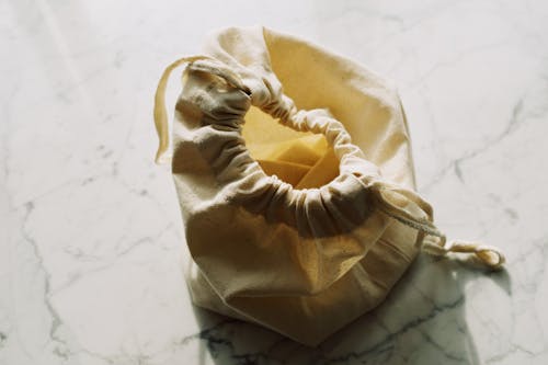 Free From above view of small zero waste textile bag with drawstrings placed on white marble table in light room Stock Photo