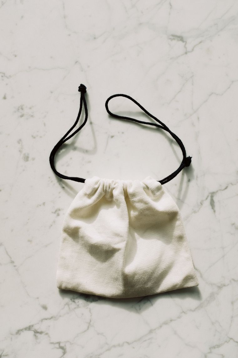 Natural textile bag with dark drawstrings, seen from above - photo by ready made on Pexels