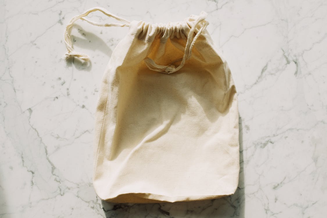 White textile bag with drawstrings placed on marble table