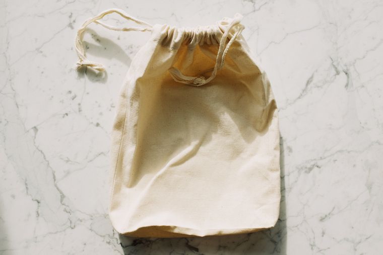 Empty cotton sack with drawstrings on a pale surface - photo by ready made on Pexels