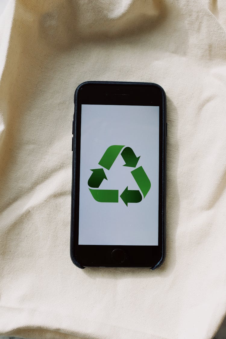 Smartphone With Recycling Symbol On Screen Placed On White Textile Surface