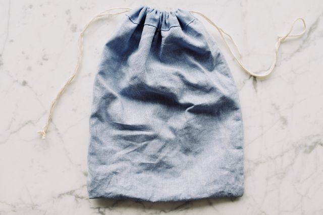 Trousse artisanale en tissu bleu clair posée à plat sur un fond de marbre