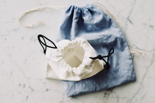 Free Top view of composed blue and white modern plain fabric bags on marble table in room Stock Photo