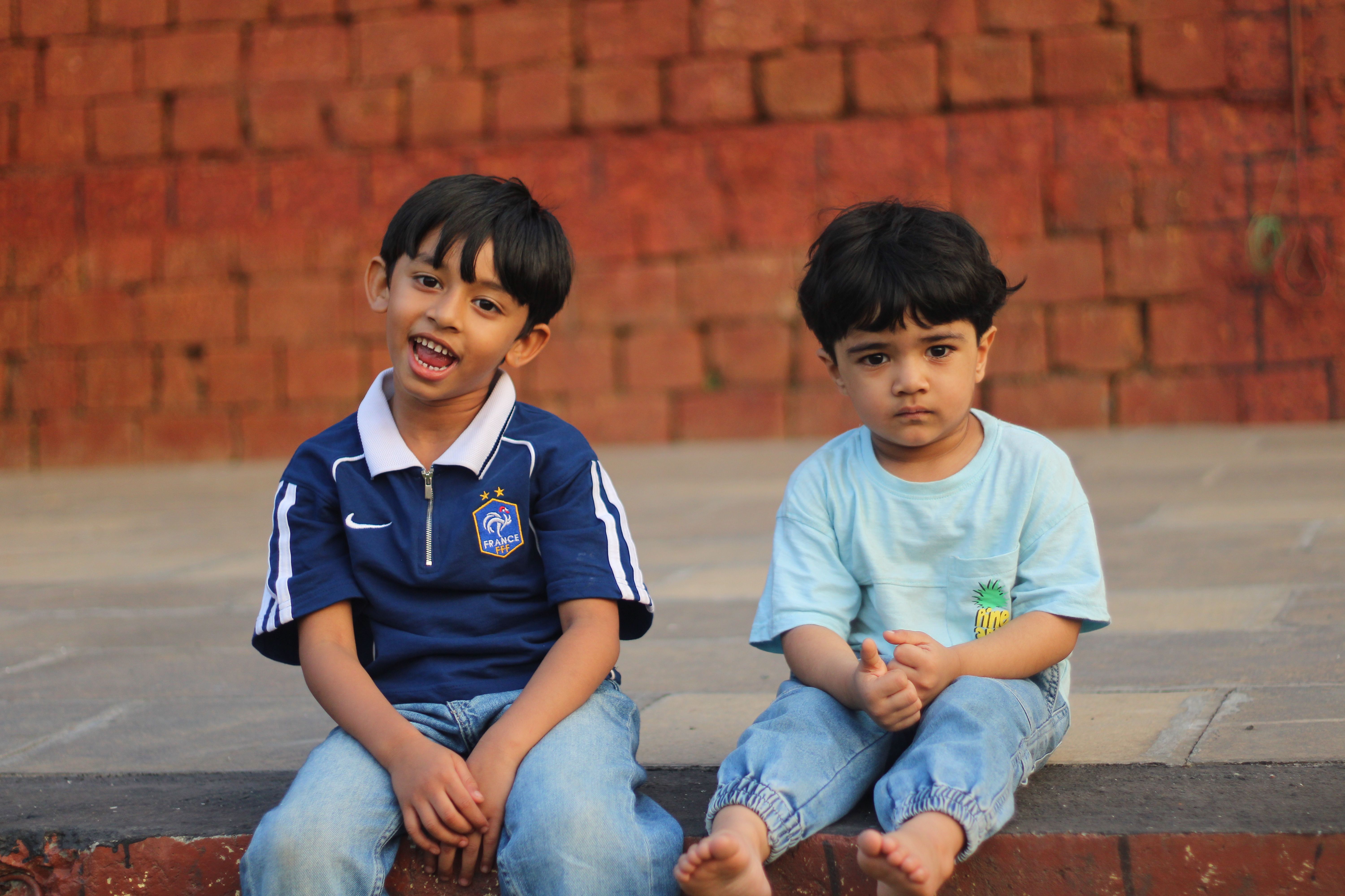 Two young boys sitting outdoors in casual everyday clothing