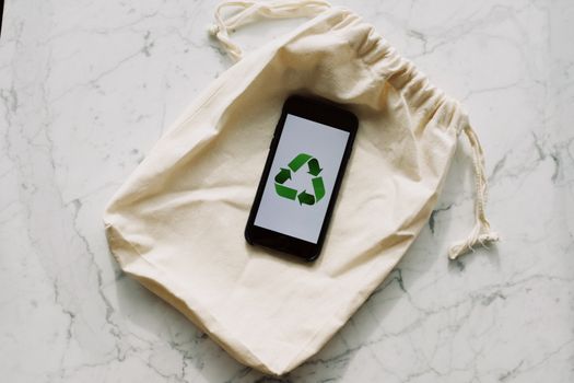 Smartphone displaying recycling icon on a drawstring pouch. Eco-conscious and sustainable theme.