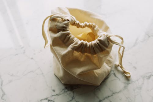 Top view of plain white fabric sack with drawstrings placed on marble table in room