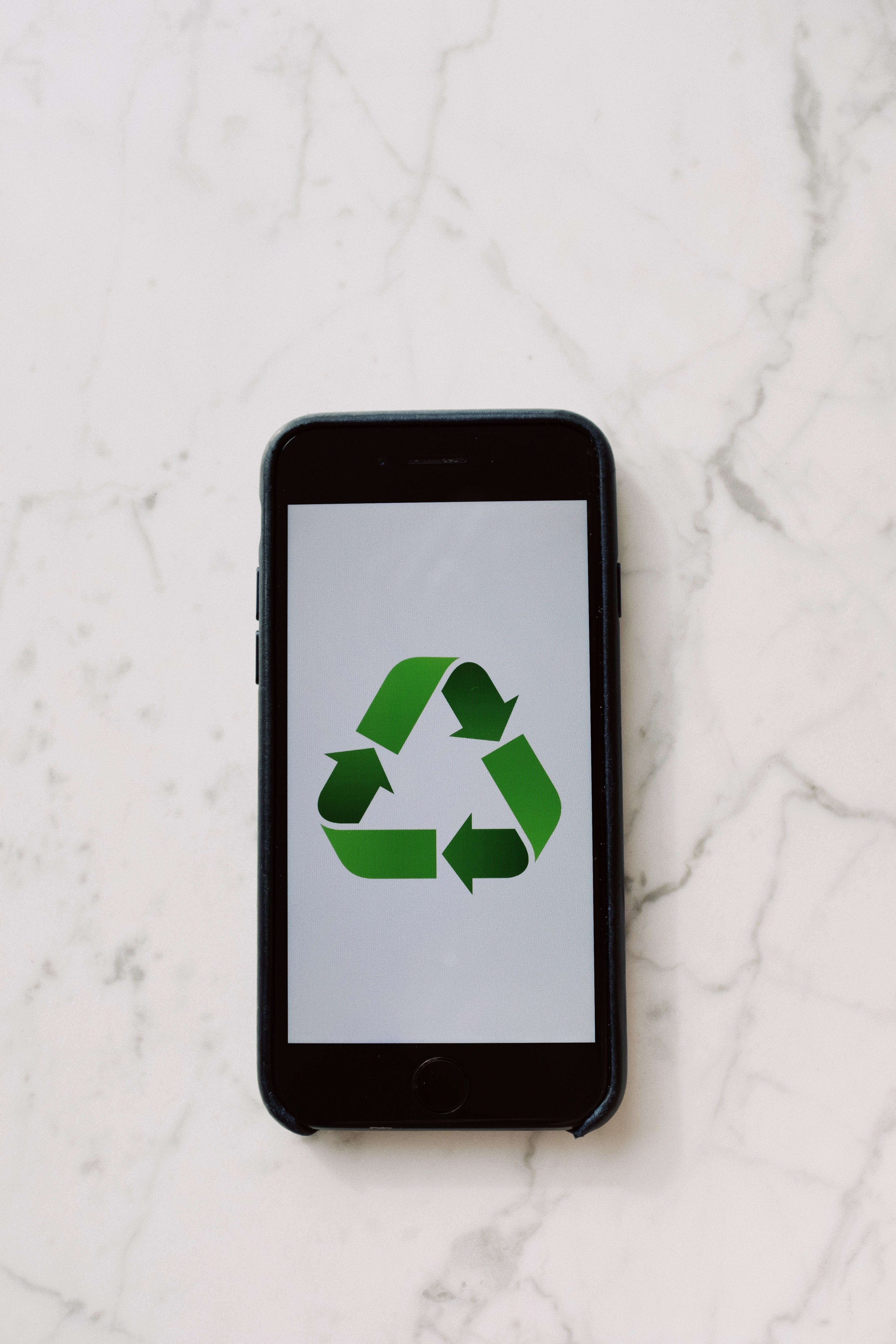 Mobile phone displaying a green recycling symbol, symbolizing sustainable technology.