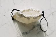 A simple canvas drawstring pouch placed on a marble background, captured in natural light.