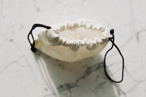 Free A simple canvas drawstring pouch placed on a marble background, captured in natural light. Stock Photo