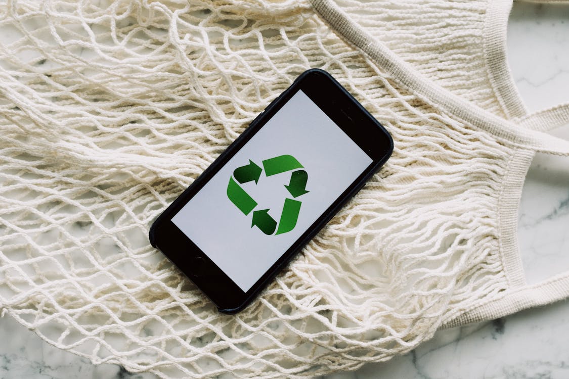 Free Smartphone with green recycle symbol and mesh bag Stock Photo