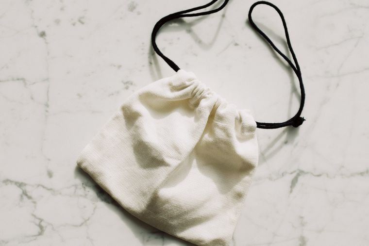 White canvas drawstring pouch on a pale marble surface - photo by ready made on Pexels