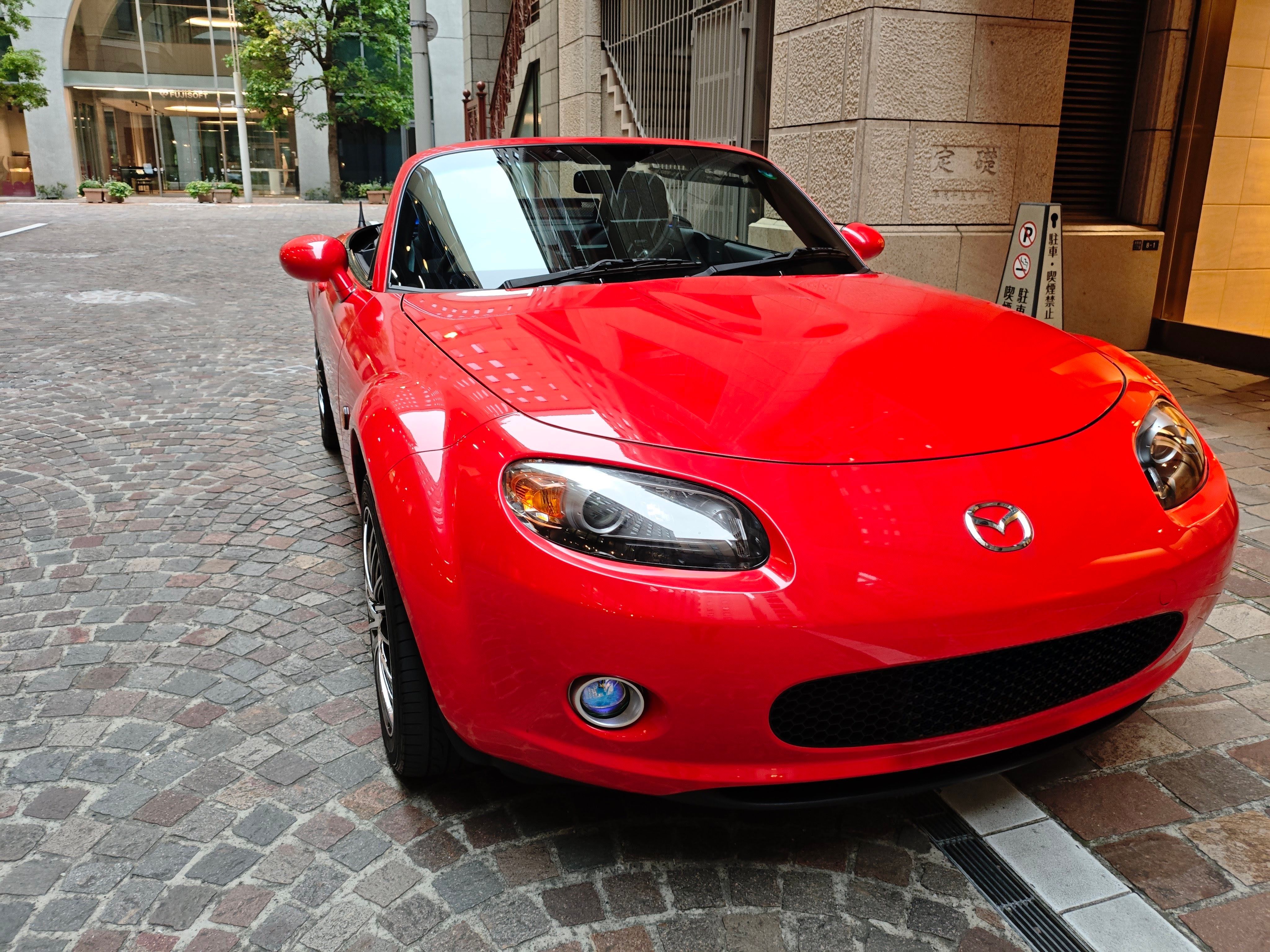 Red convertible sports car parked on a cobblestone street.