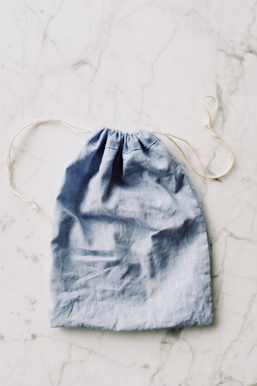 Free From above view of blue fabric zero waste sack with white drawstrings placed on white marble surface in light room Stock Photo