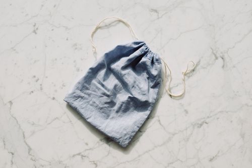Free A blue reusable fabric pouch lying on a textured marble surface, showcasing eco-friendly storage. Stock Photo