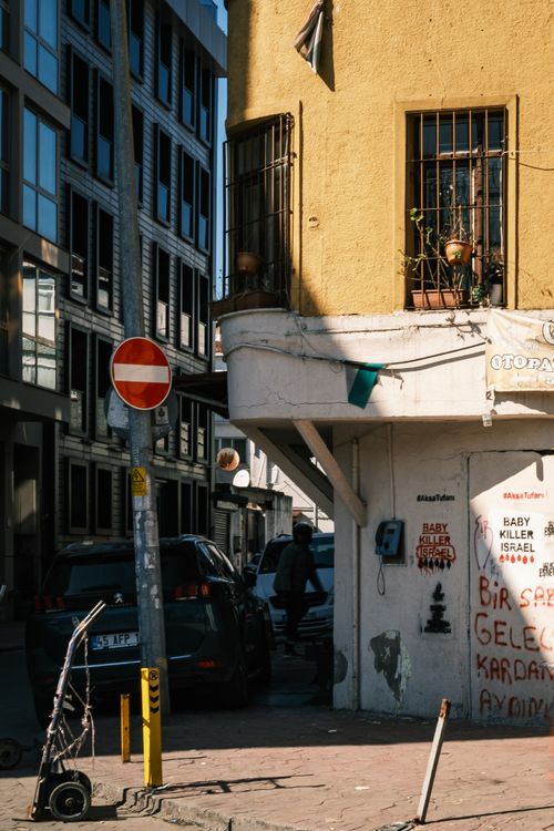 Free City street scene featuring graffiti on a building corner with urban architecture and vehicles. Stock Photo