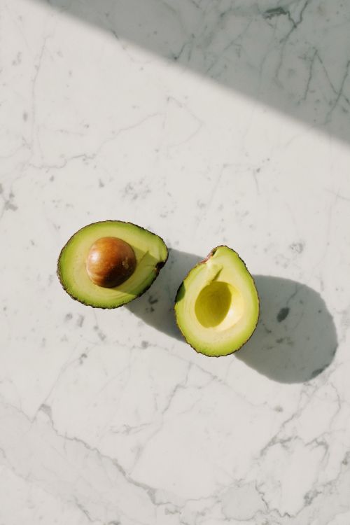 Free Top view of fresh avocado halves on a marble surface, showcasing vibrant green color. Stock Photo