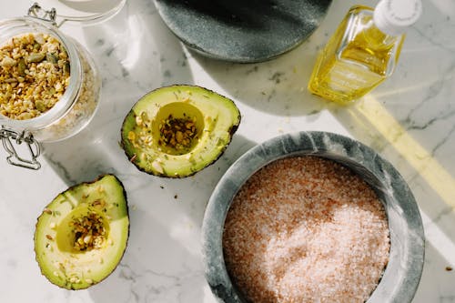 Fresh avocado halves with seed mix and other ingredients for healthy breakfast