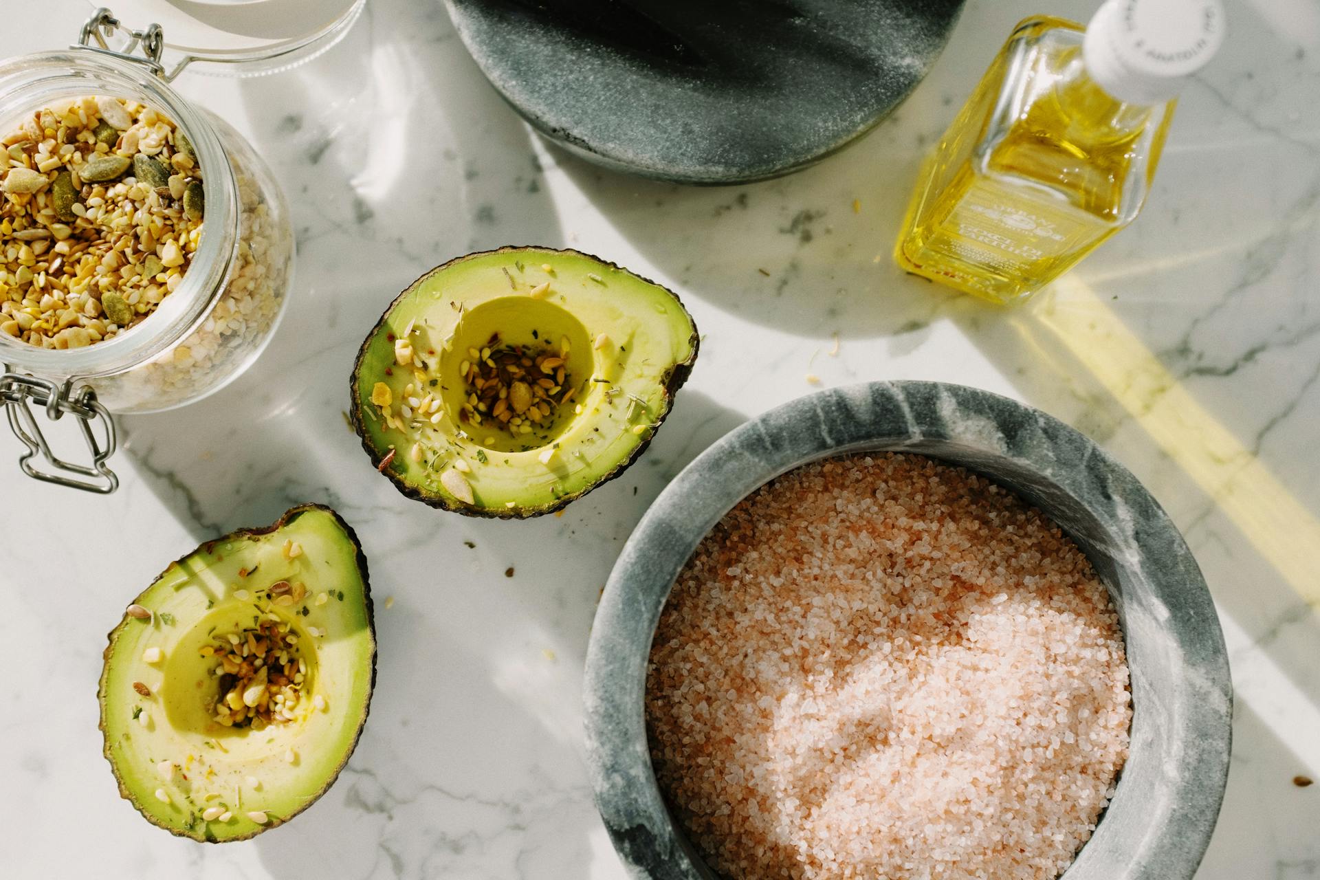 Fresh avocado halves with seed mix and other ingredients for healthy breakfast