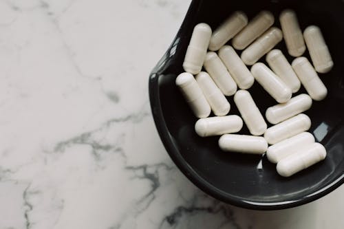 White Medication Pill on Black Ceramic Bowl