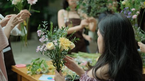 Free A florist workshop with adults creating floral arrangements in a cozy setting. Stock Photo