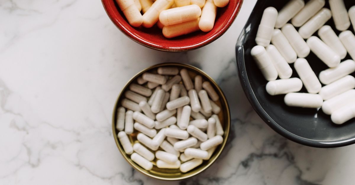 Top view of various capsules in bowls placed on a marble surface, emphasizing healthcare and medication themes.
