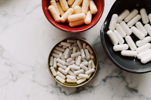Top view of various capsules in bowls placed on a marble surface, emphasizing healthcare and medication themes.