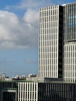 A modern high-rise building against a backdrop of blue sky and clouds, capturing urban architecture.