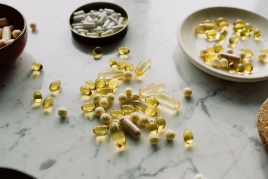 A collection of capsules and tablets on a marble surface, highlighting healthcare and wellness.