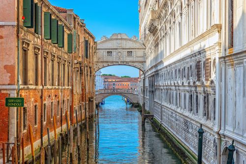 Free A breathtaking view of Venice's Bridge of Sighs spanning a serene canal under a bright blue sky. Stock Photo