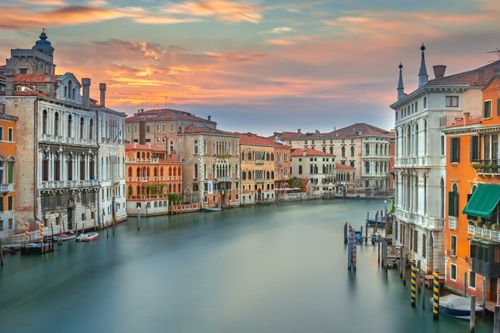 Free Charming architecture and serene waters of a Venetian canal at sunset. Stock Photo