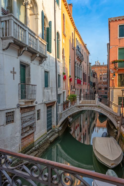 Free Picturesque view of a Venetian canal with colorful historic buildings at sunset. Stock Photo