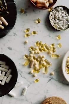Capsules in transparent gelatin shell and dragees placed between medical remedies in different plates on white table in studio