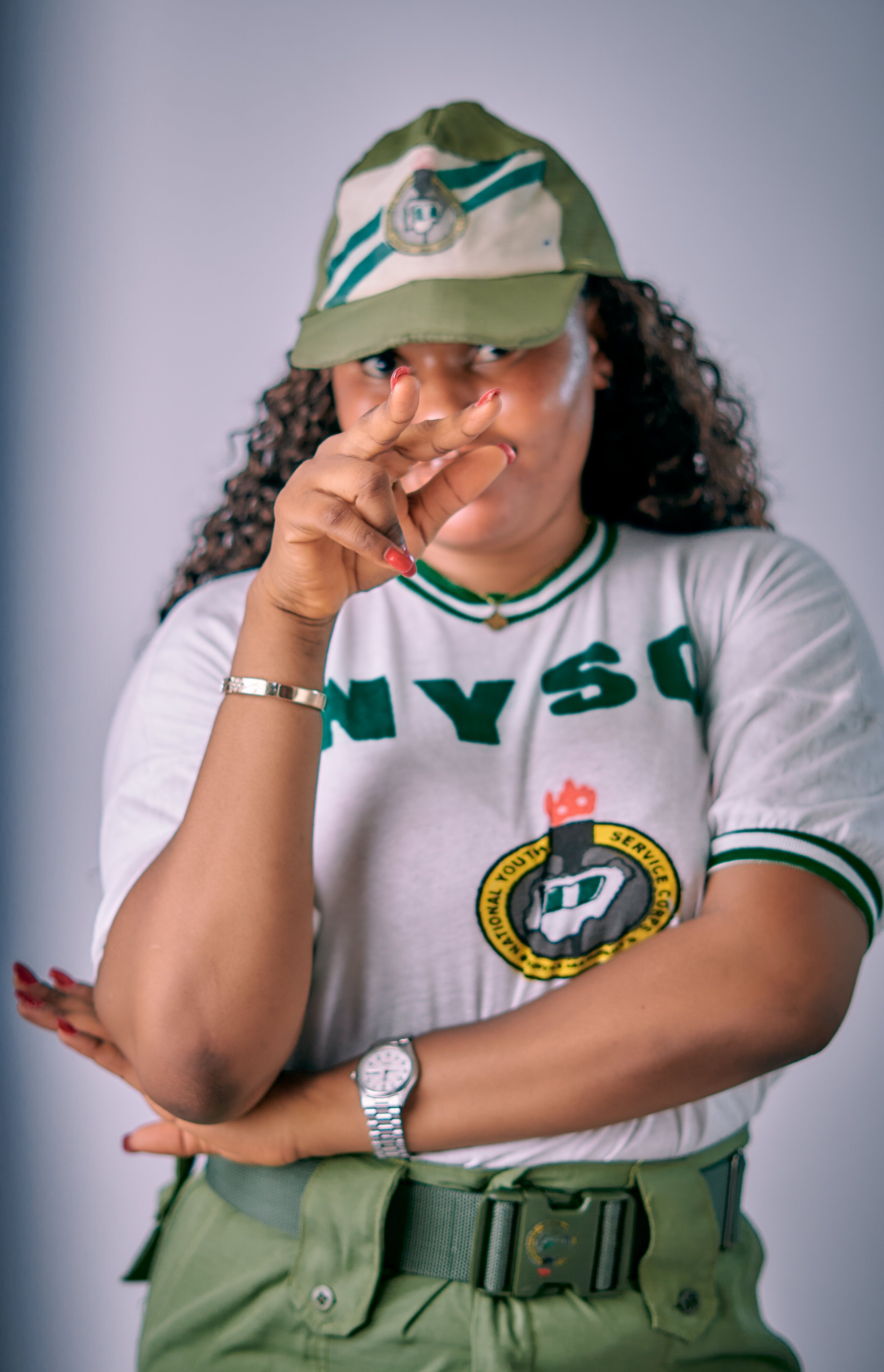 Confident NYSC member in uniform saluting proudly, Nigeria setting.