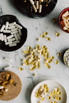 Flat lay of various pills and capsules on a marble surface for healthcare and medicine concepts.