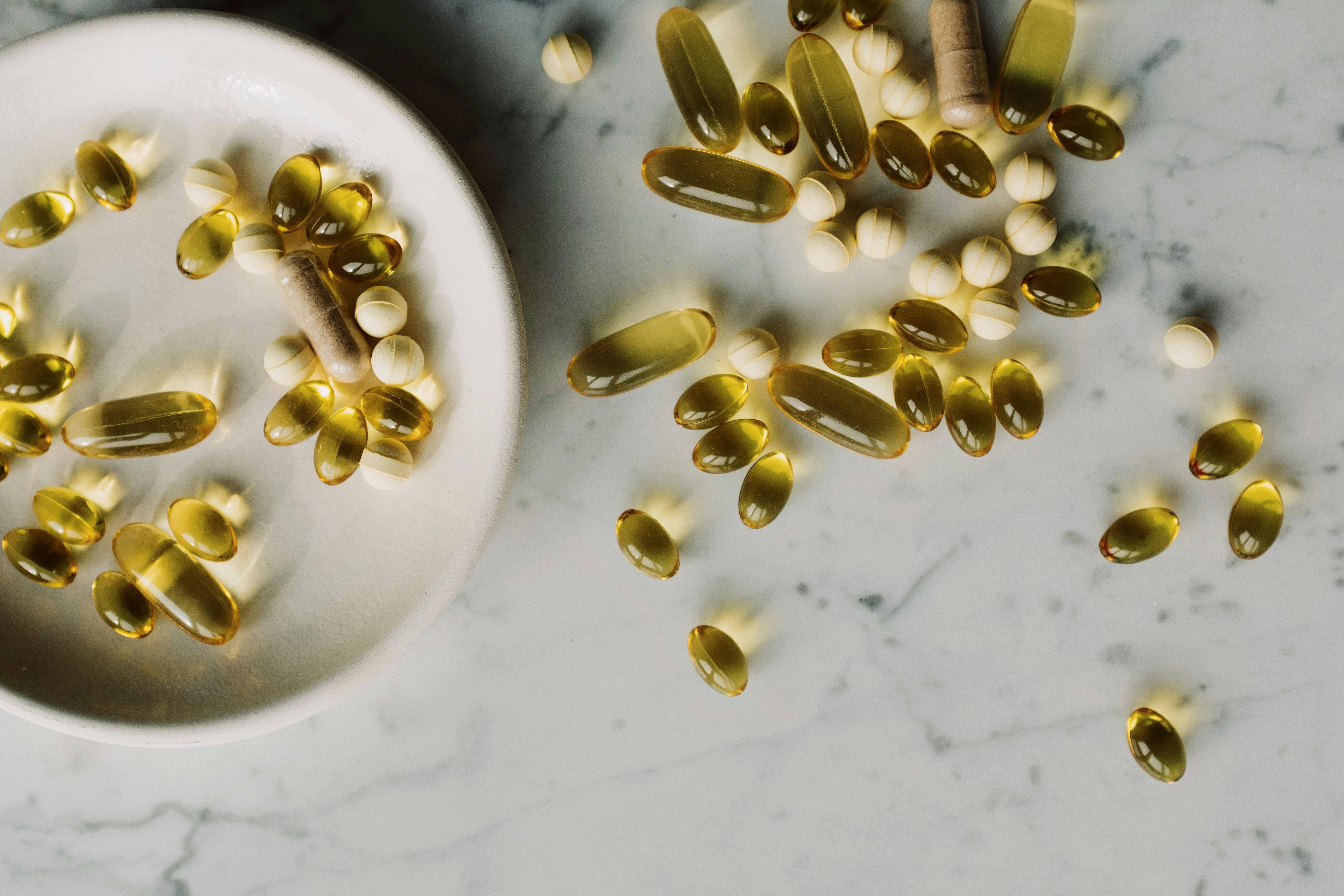 medication pills and yellow capsules of omega on table and ceramic plate