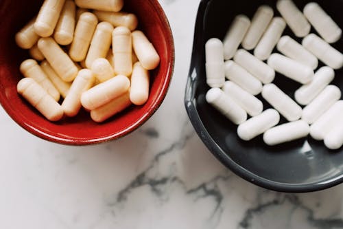 White Medication Pills on Red and Black Ceramic Bowls