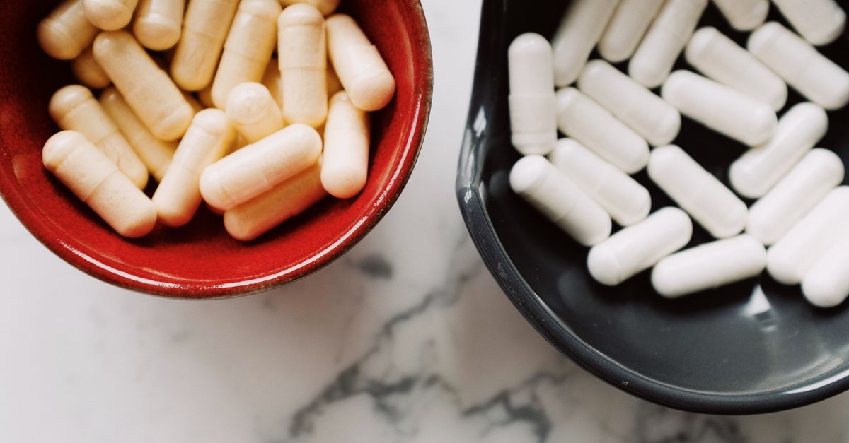 Two bowls with capsules on a marble surface, representing healthcare or medicine concepts.