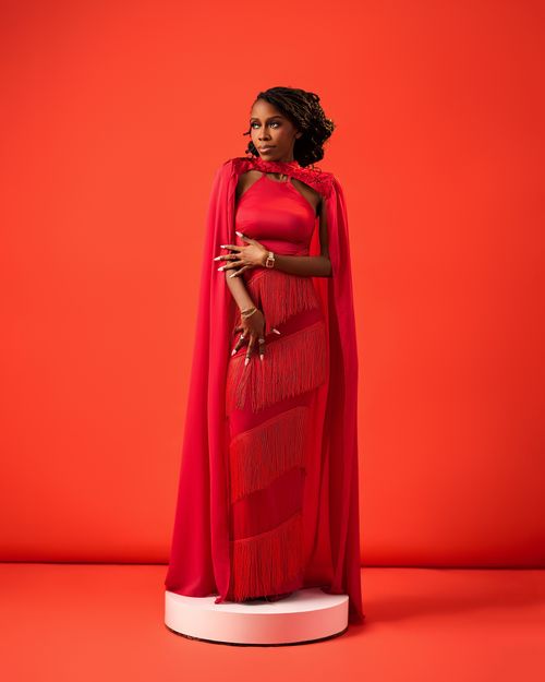 Free Stylish woman in a vibrant red gown with cape posing confidently on a revolving pedestal. Stock Photo